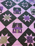 A close-up of a Spooky version of the Vintage Farmhouse pattern featuring blacks, greys and purples with fussy-cut ghosts in the windows!