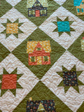 Quilt with star patterns and small house designs in various colors.